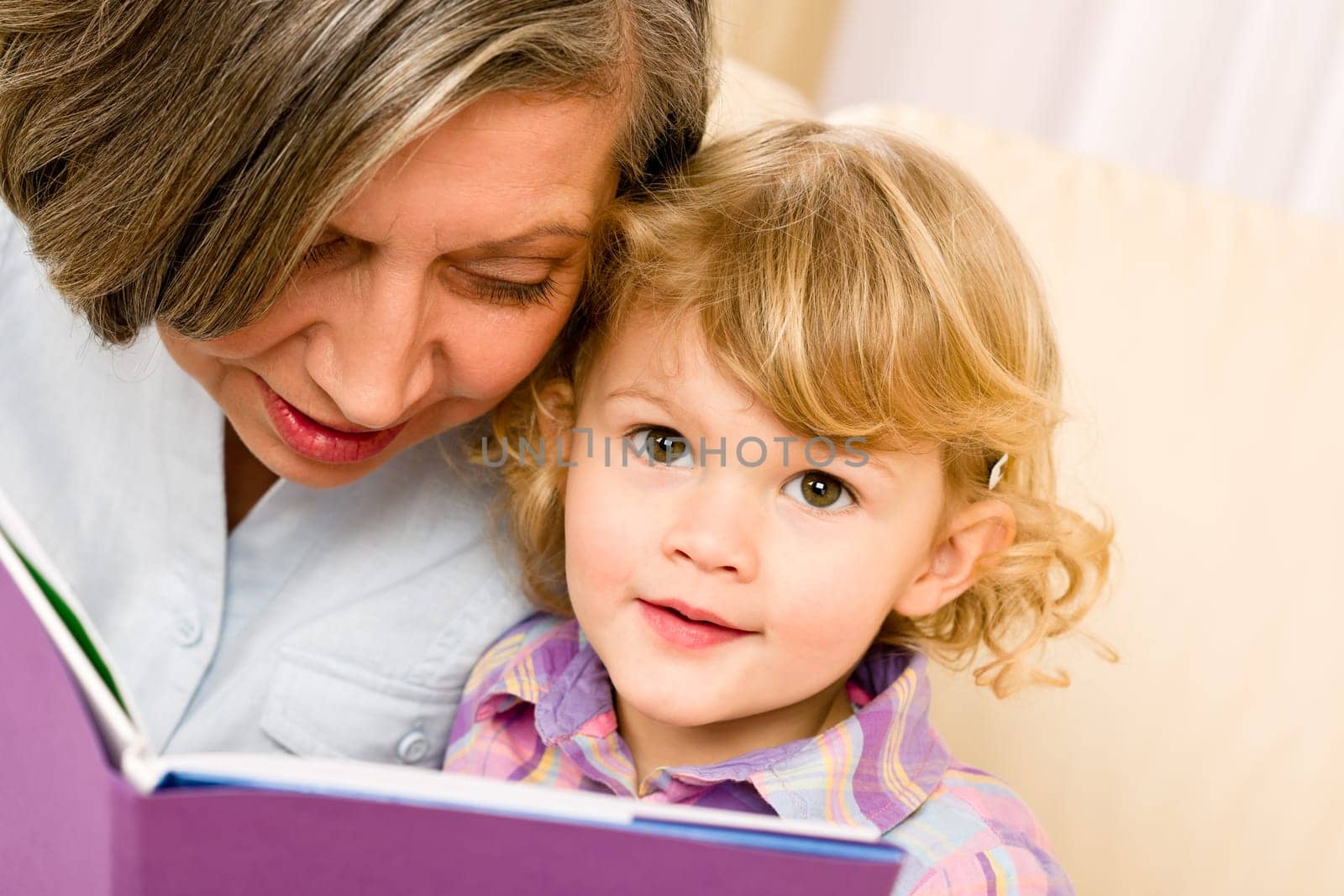 Grandmother and little girl reading book happy together at home