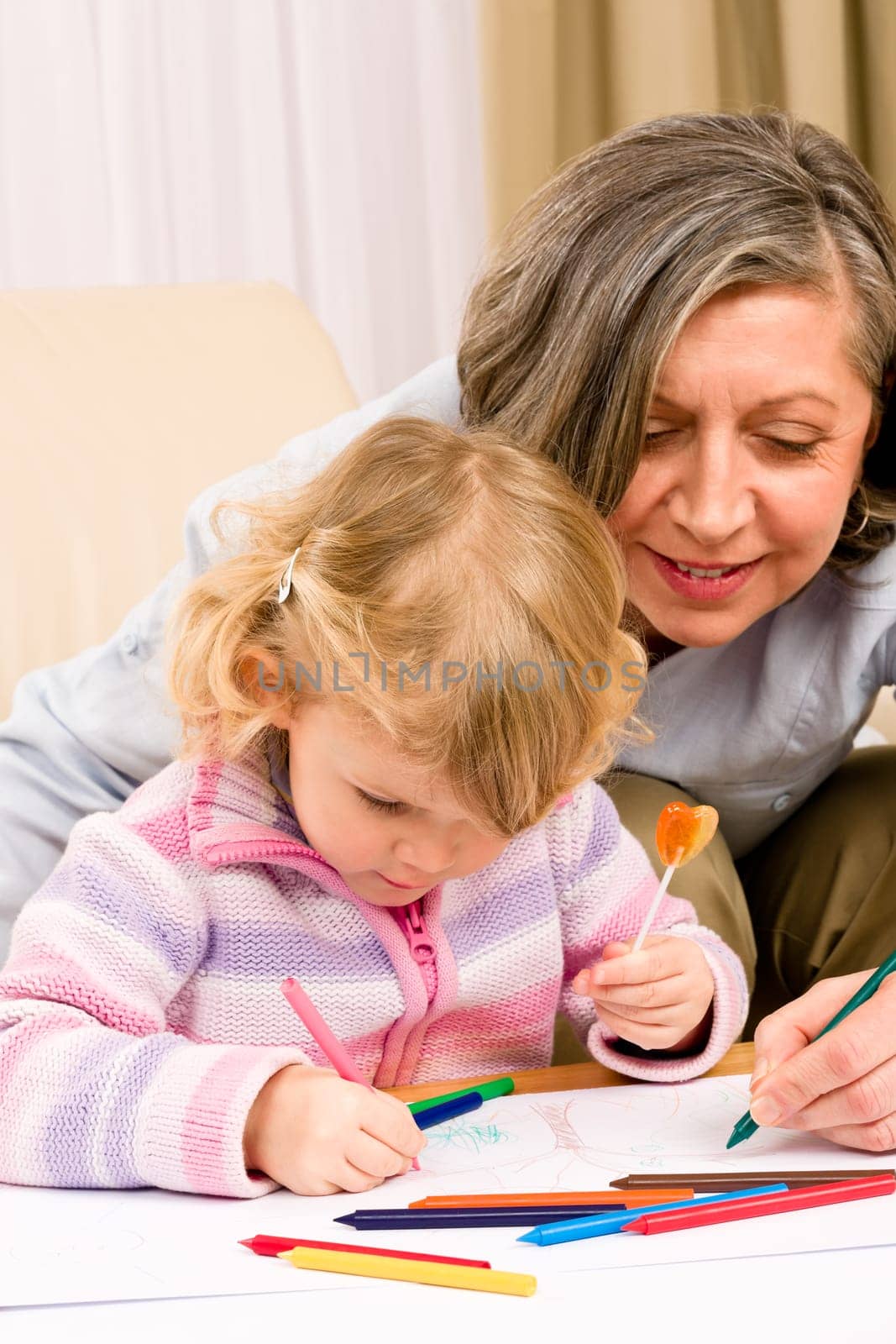 Grandmother and granddaughter drawing together with pencils