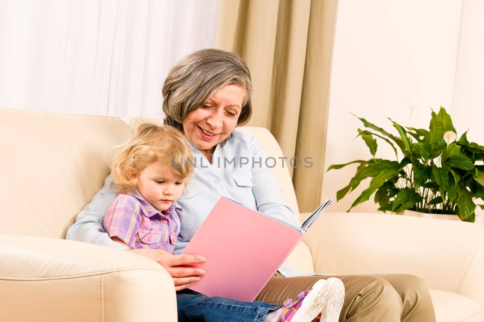 Grandmother and little girl reading book happy together at home