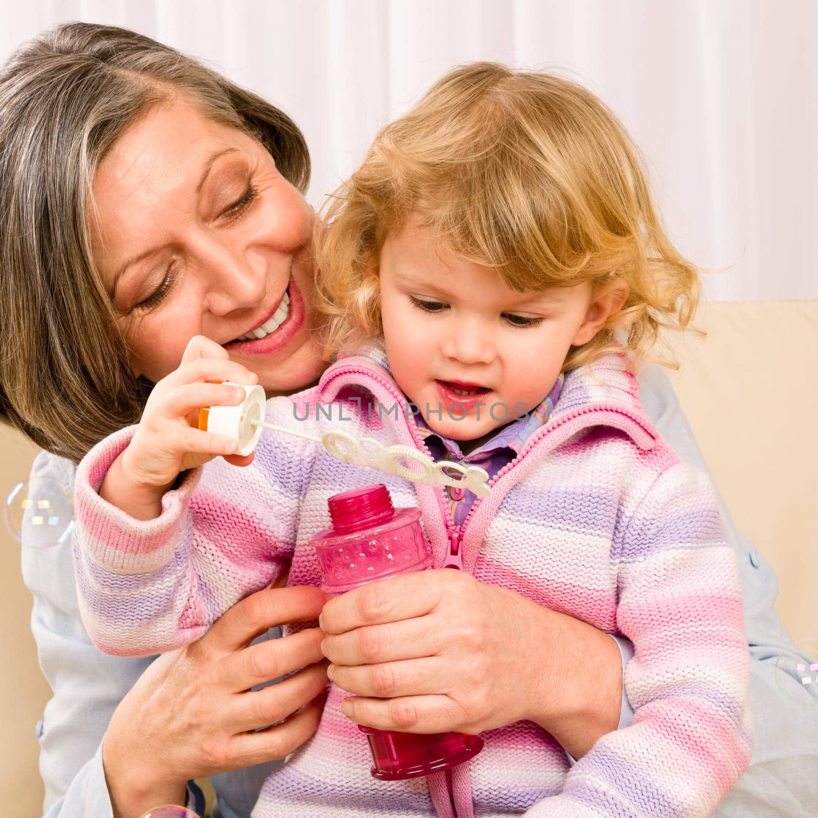 Little granddaughter with grandmother make bubble blower play happy together