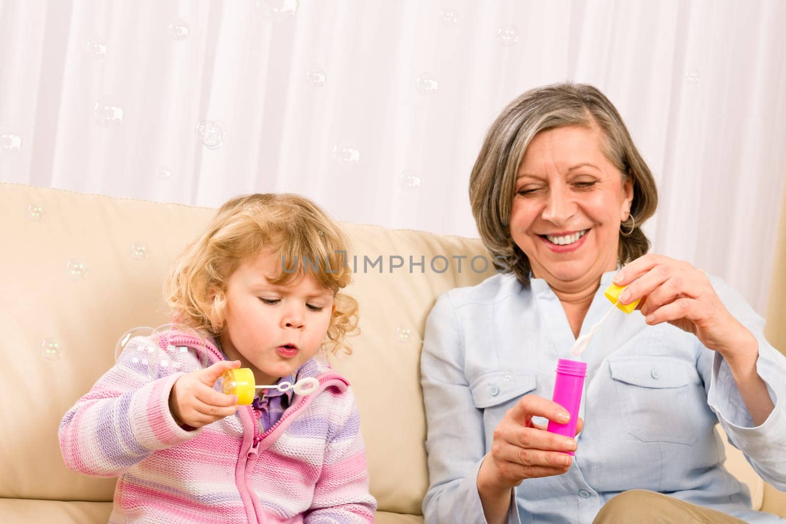 Little granddaughter with grandmother make bubble blower play happy together