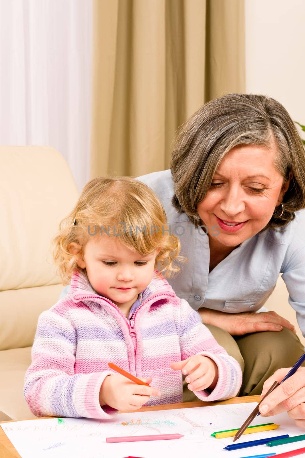 Grandmother and granddaughter drawing together with pencils at home