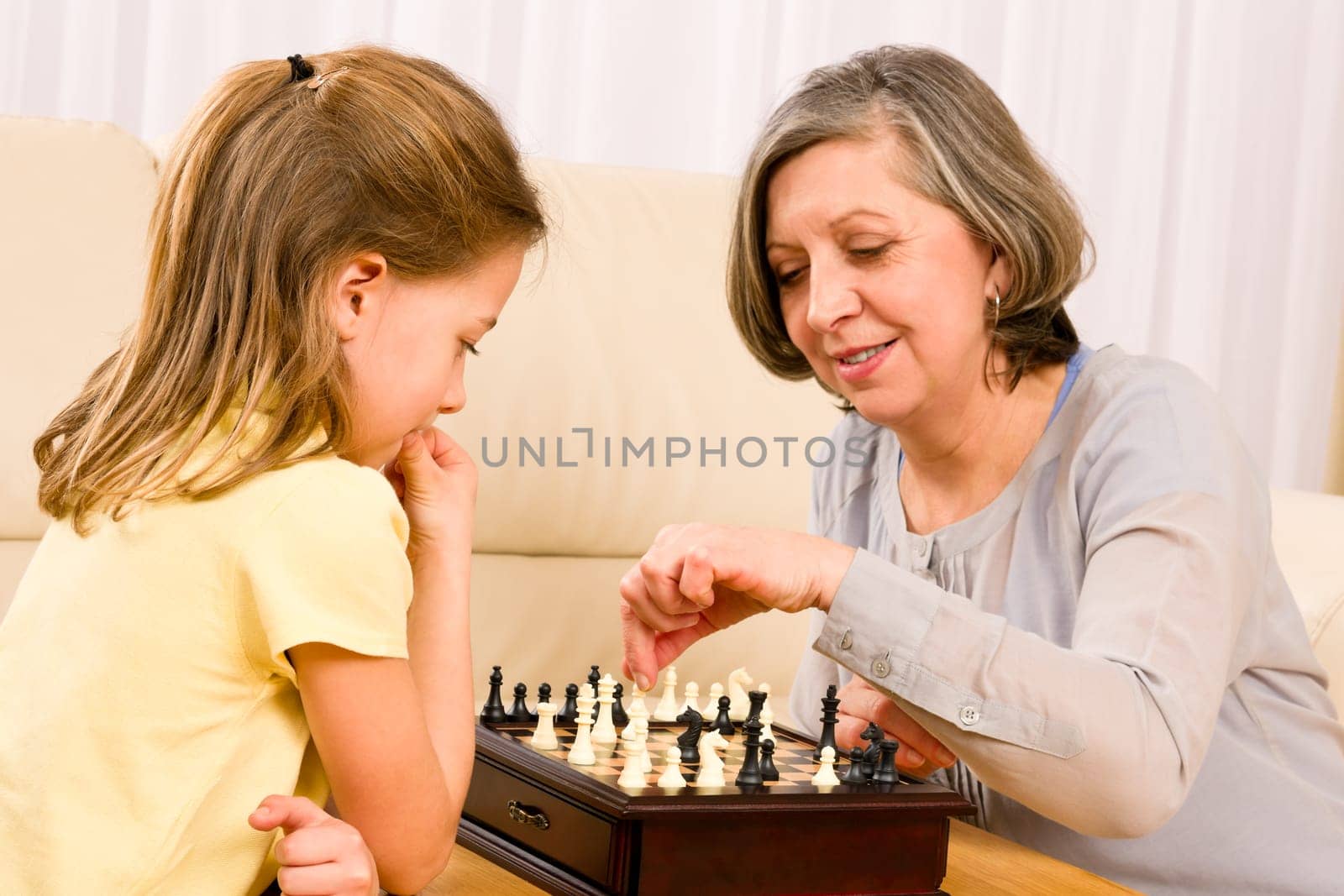 Grandmother and young girl playing chess together at home