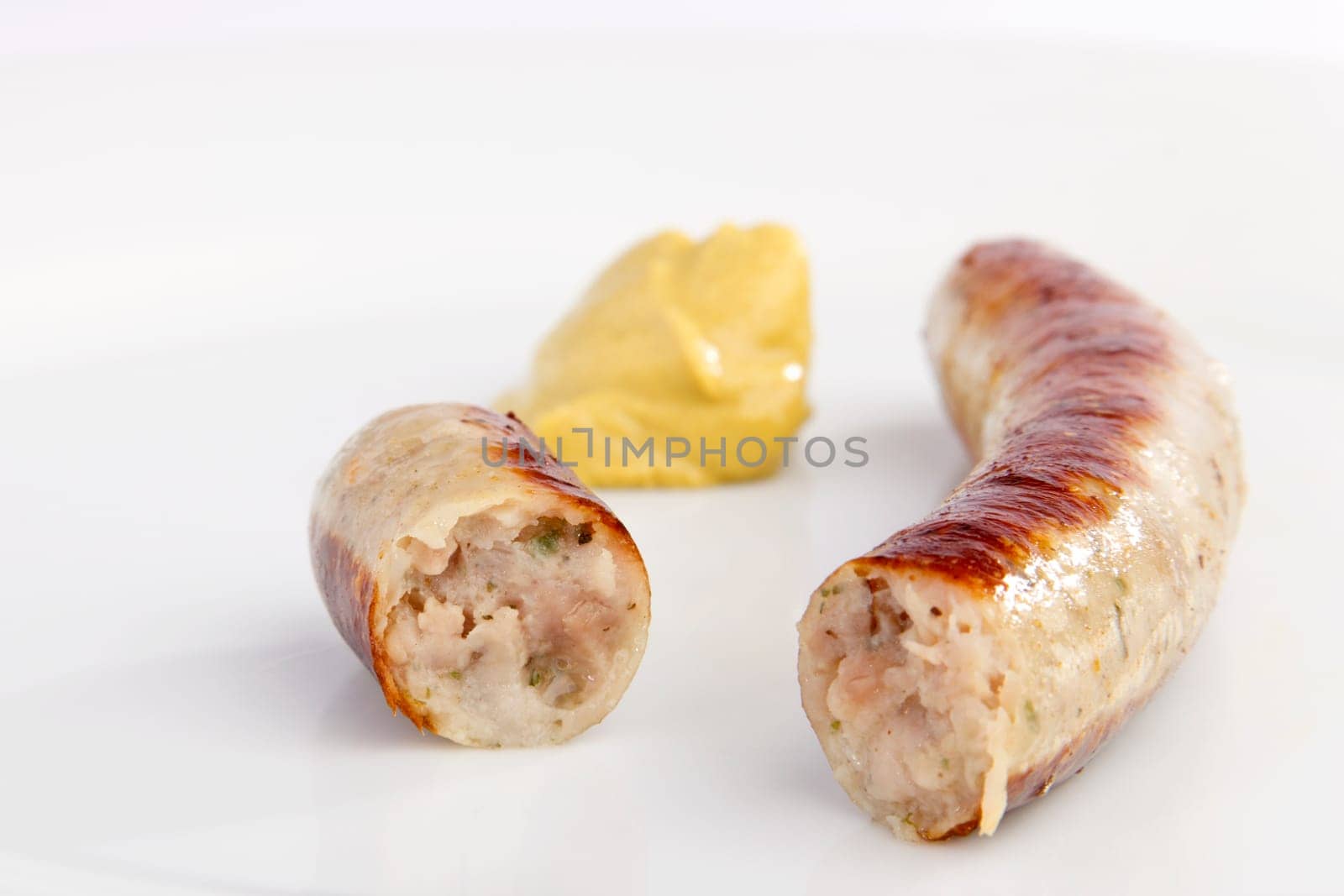 Sliced bratwurst with mustard on white background