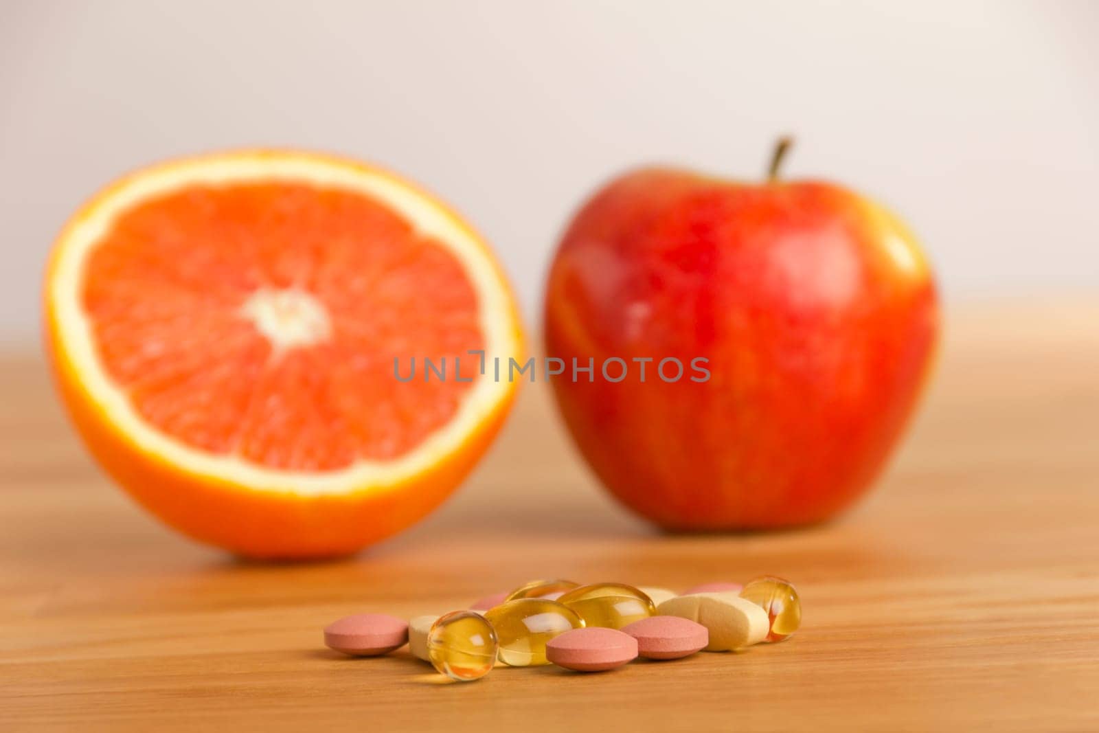 Tablets lie on a table in the background a halved orange and an apple