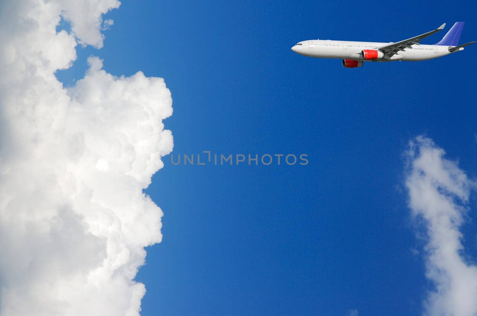 large airliner flying into puffy white cloud formation