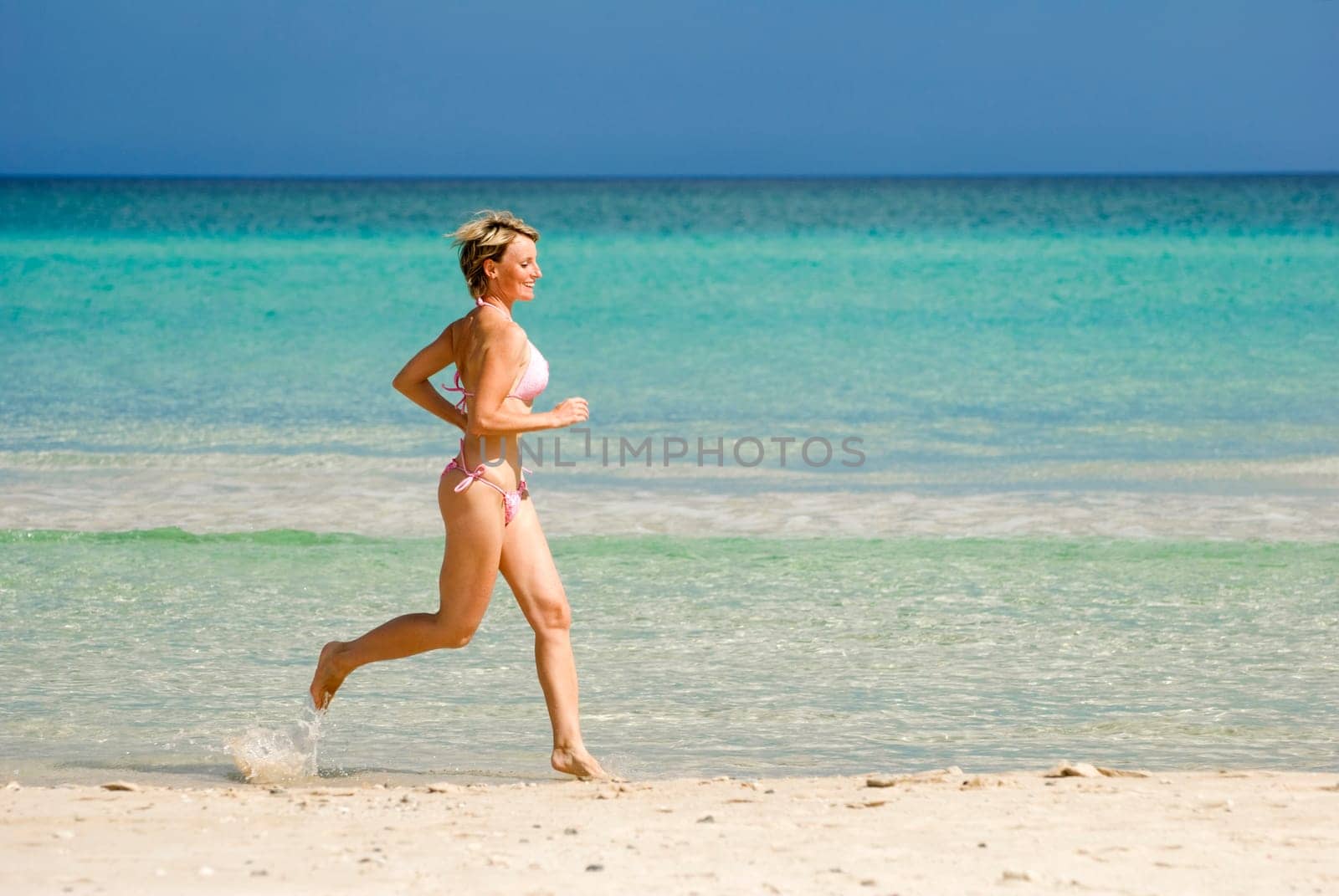young blond woman running on the beach