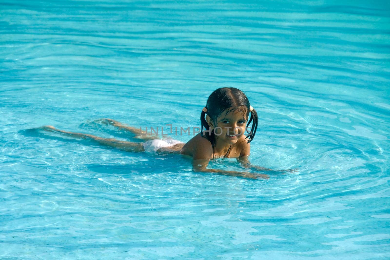 Young kid enjoying cool water laying down in a pool