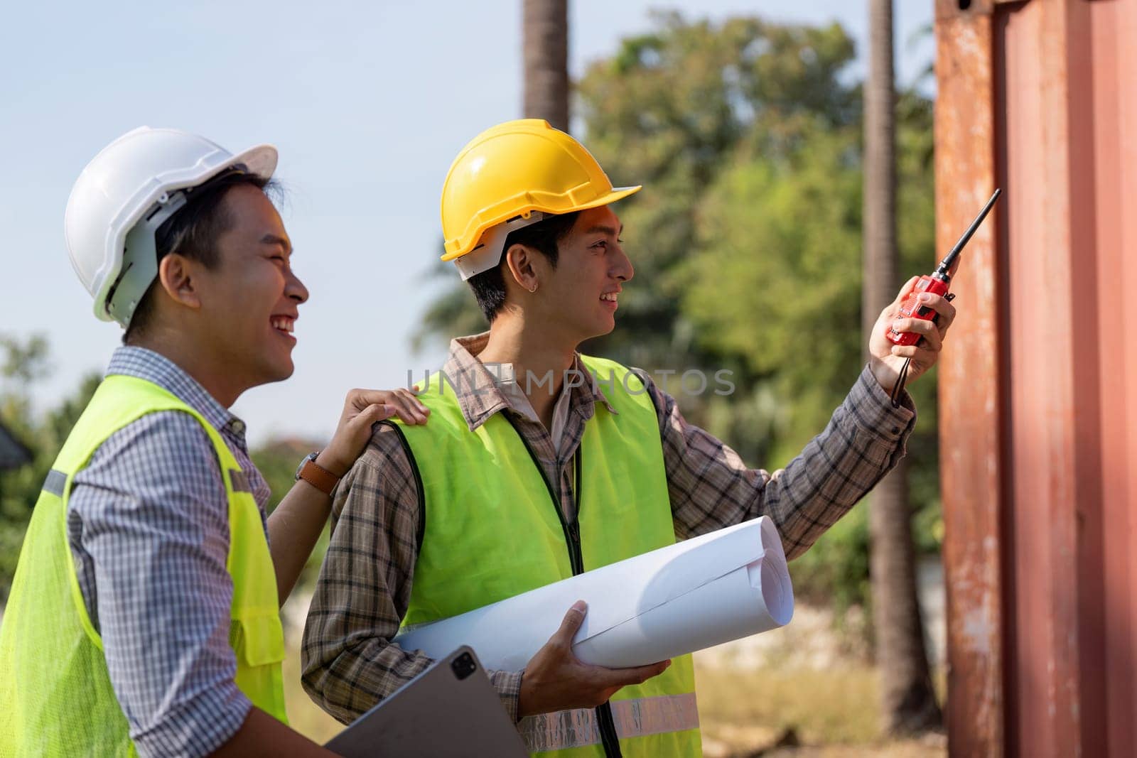 Two engineers discuss construction plans outdoors, showcasing teamwork and effective communication with blueprints.