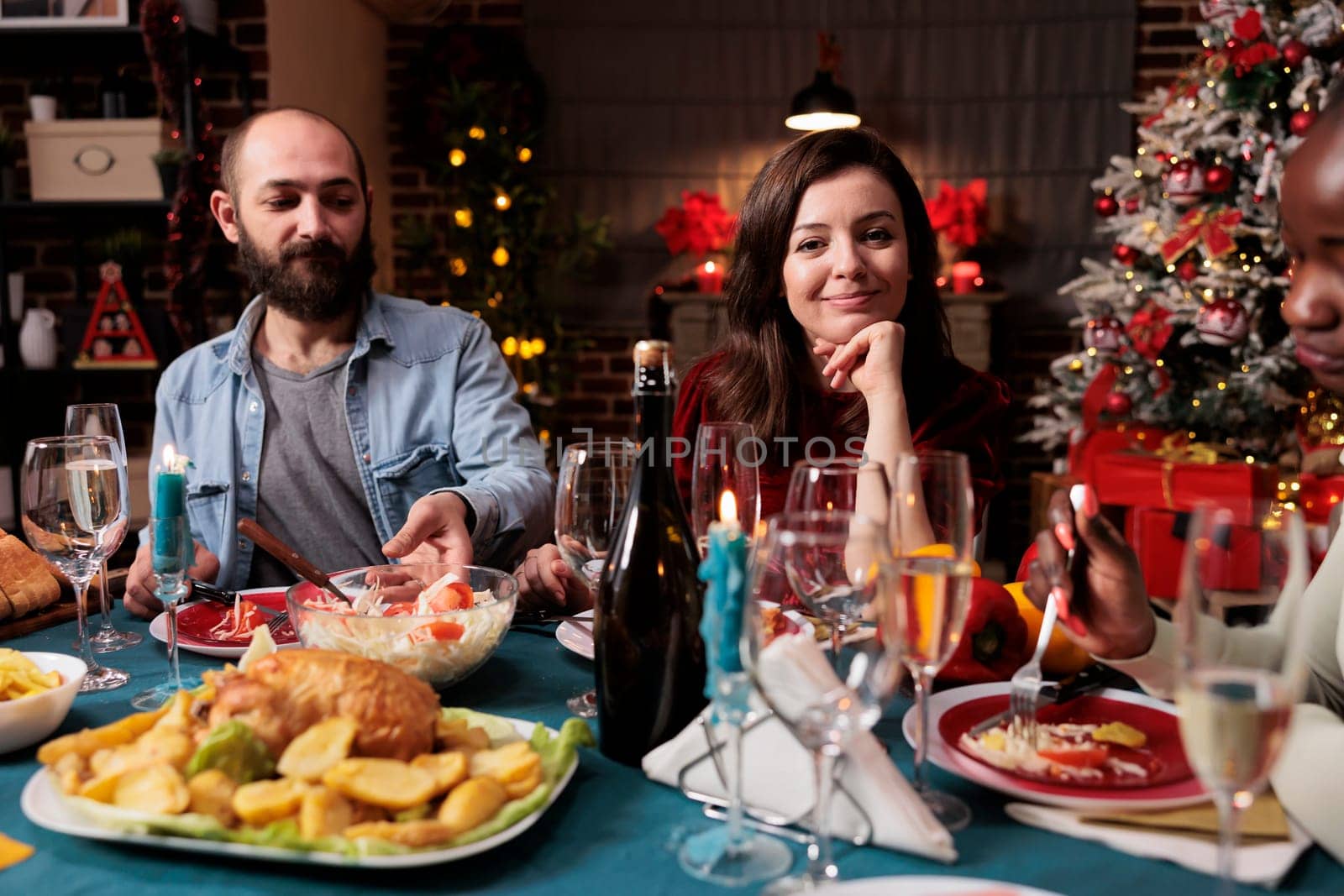 Young couple celebrating xmas with family, woman attending festive dinner during christmas eve holiday at home. Persons enjoying traditional food on the table, feeling merry and jolly.