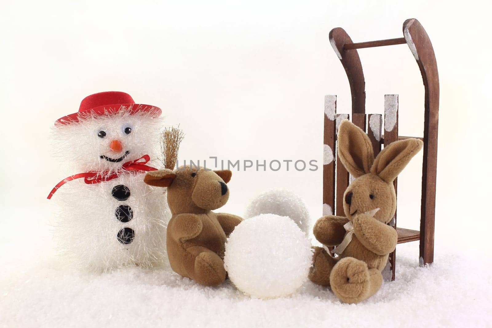 Snowman and stuffed animals having fun in winter