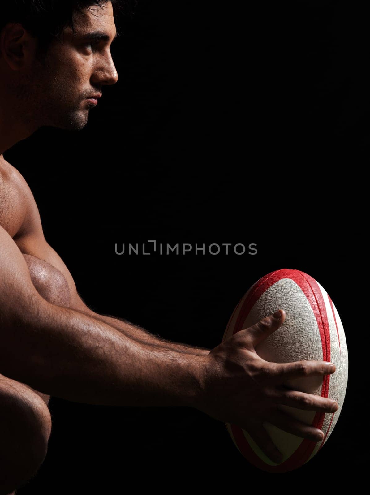 one caucasian sexy naked  man portrait holding rugby ball on studio black background