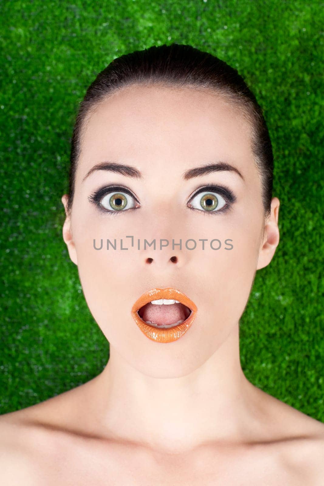 Closeup portrait of a surprised beautiful woman mouth open on green