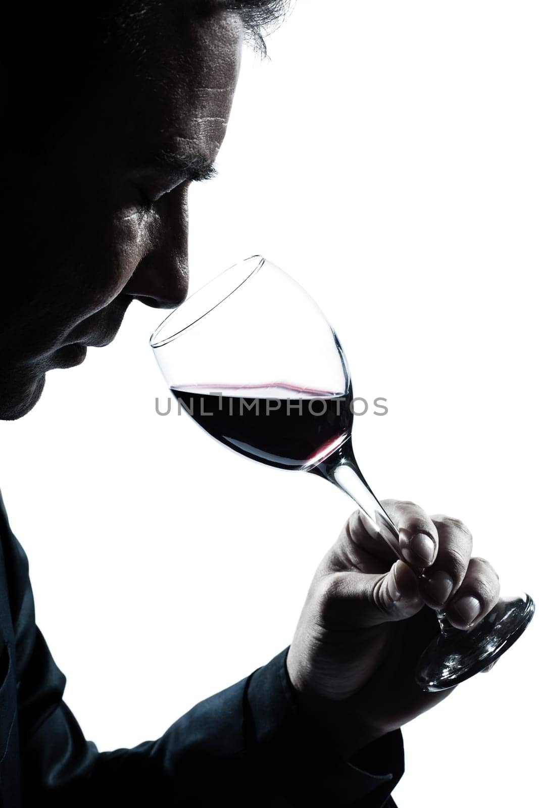 one caucasian man portrait silhouette smelling red wine glass in studio isolated white background
