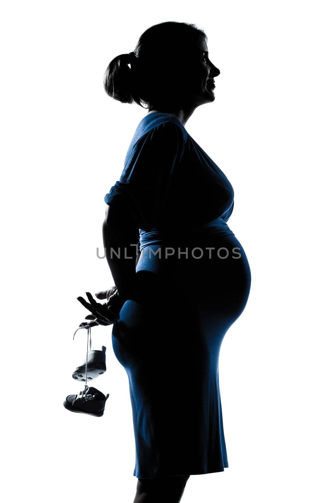 beautiful caucasian pregnant woman holding baby shoes in silhouette on studio isolated white background