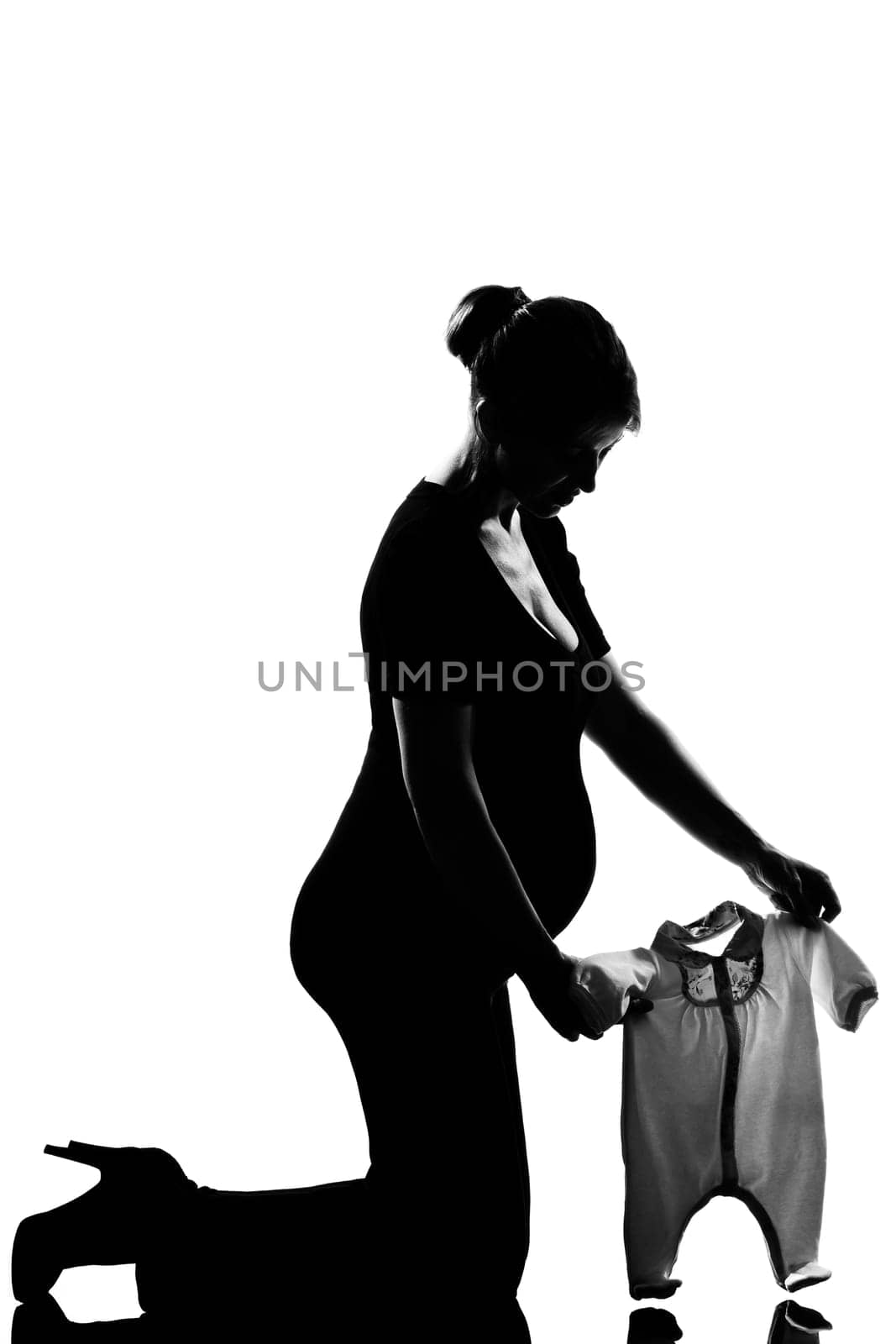 beautiful caucasian pregnant woman  baby clothes in full length silhouette on studio isolated white background
