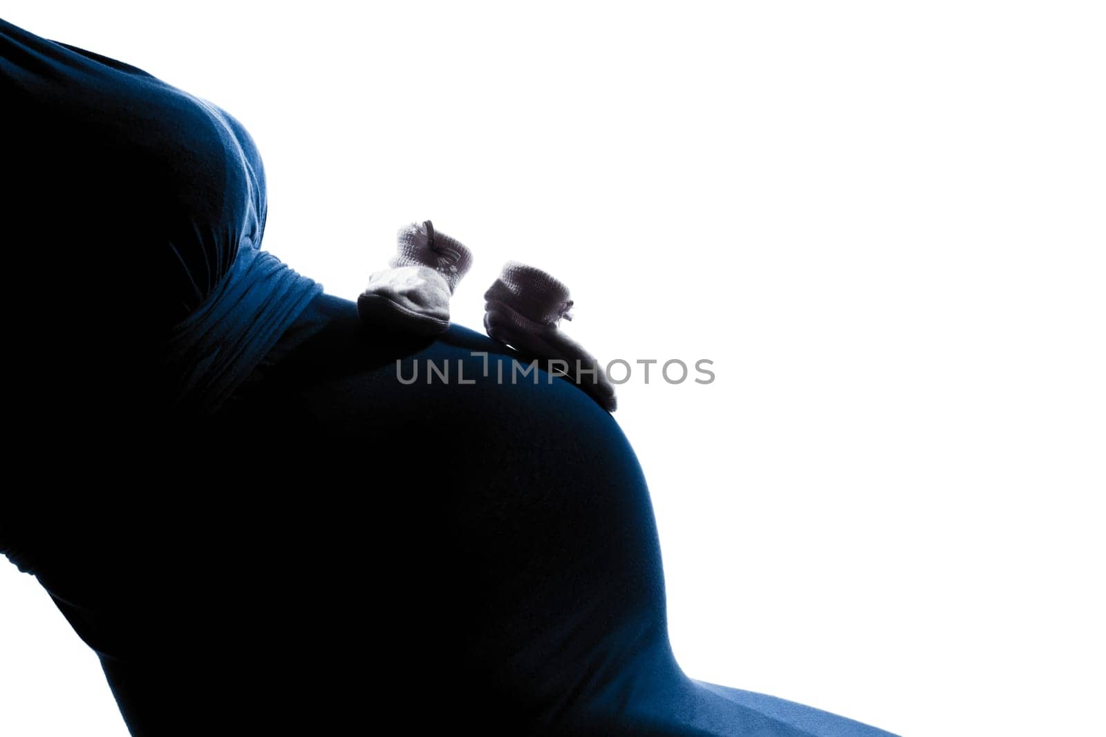 beautiful caucasian pregnant woman belly with baby shoes in silhouette on studio isolated white background