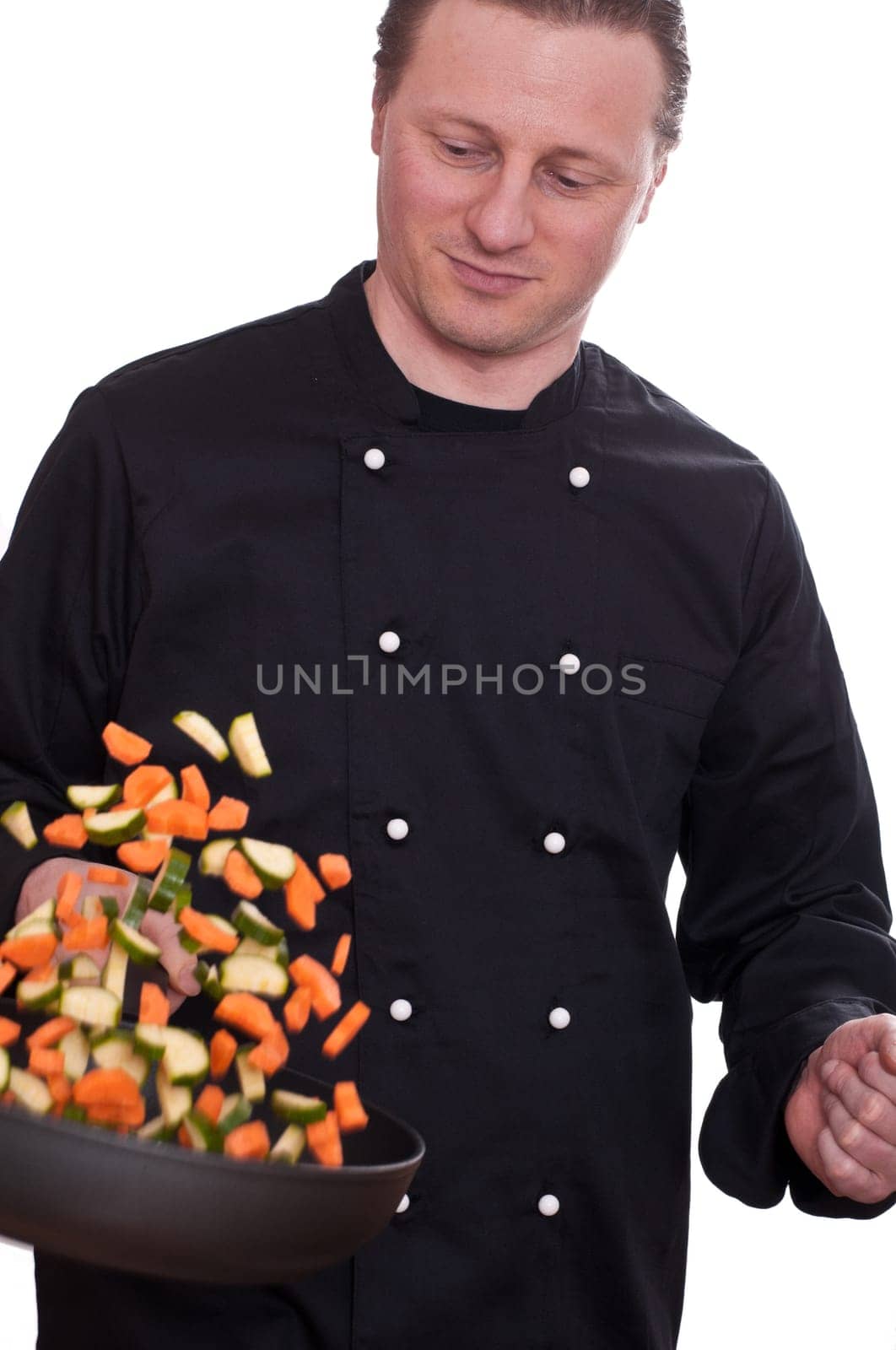 A cook turns by throwing up the vegetables in a frying pan