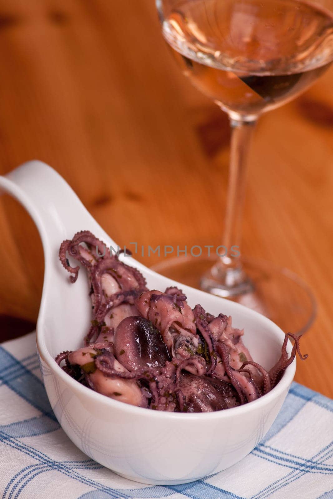 A salad of squid moscardini with herbs and a glass of wine