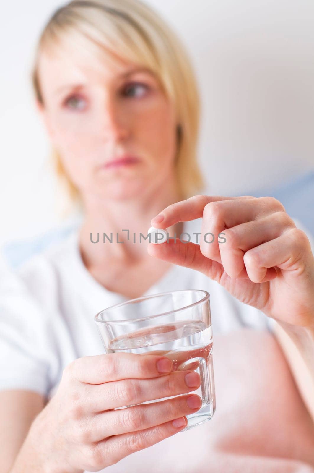 Young blond woman taking pill close up