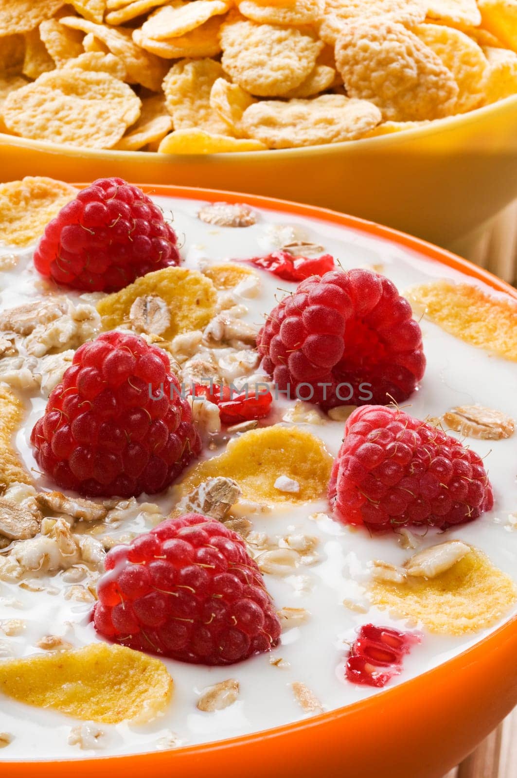 Fresh corn flakes with raspberries and milk close up