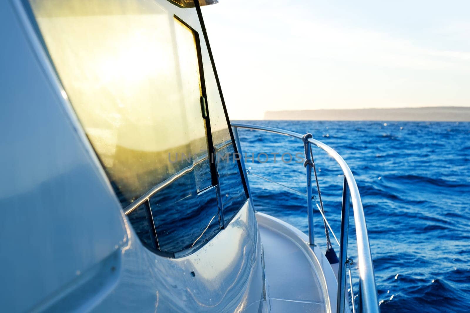 blue golden sunrise sailing on boat side with Mediterranean coastline in horizon