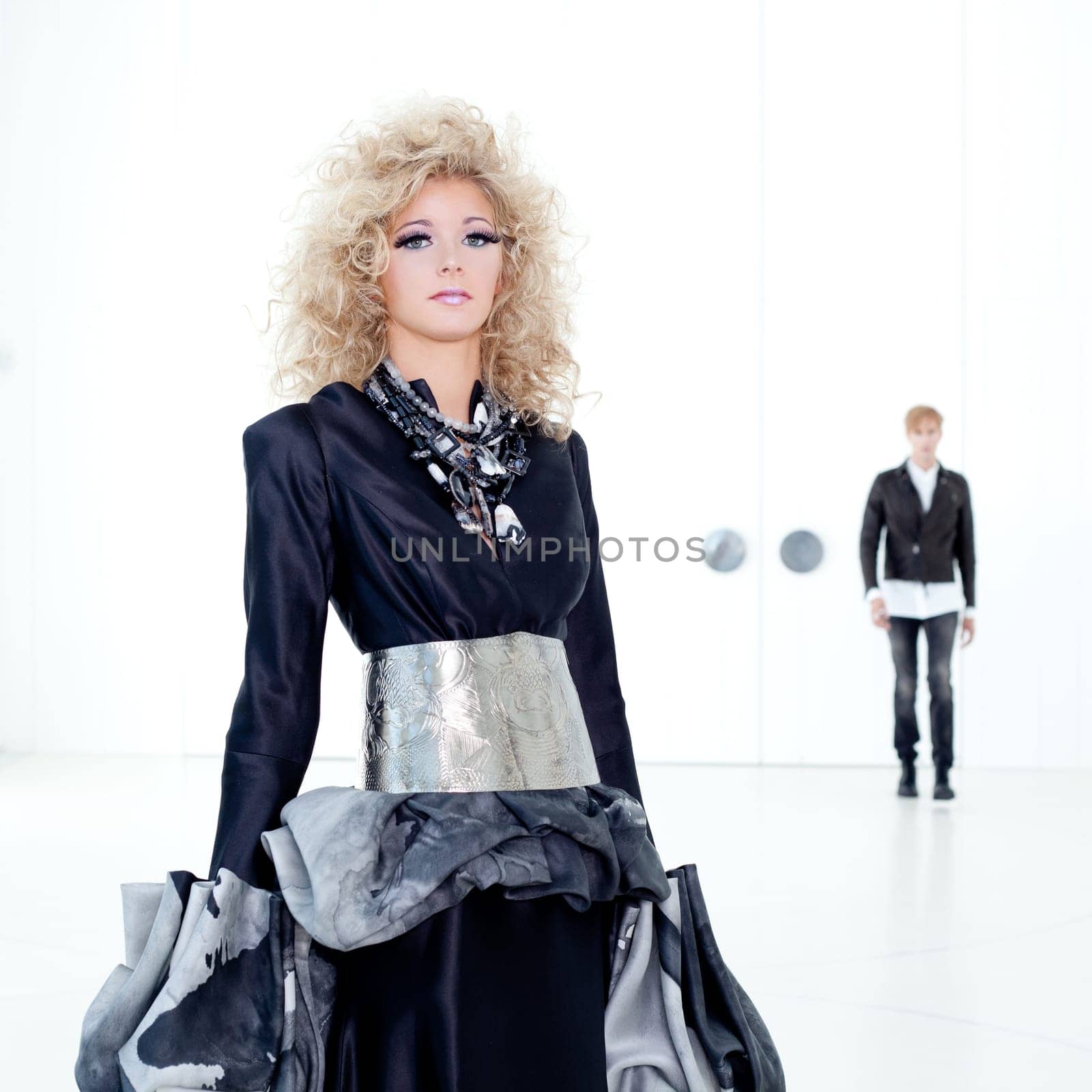 Black haute couture retro futurist couple in modern white hall with vampire inspiration