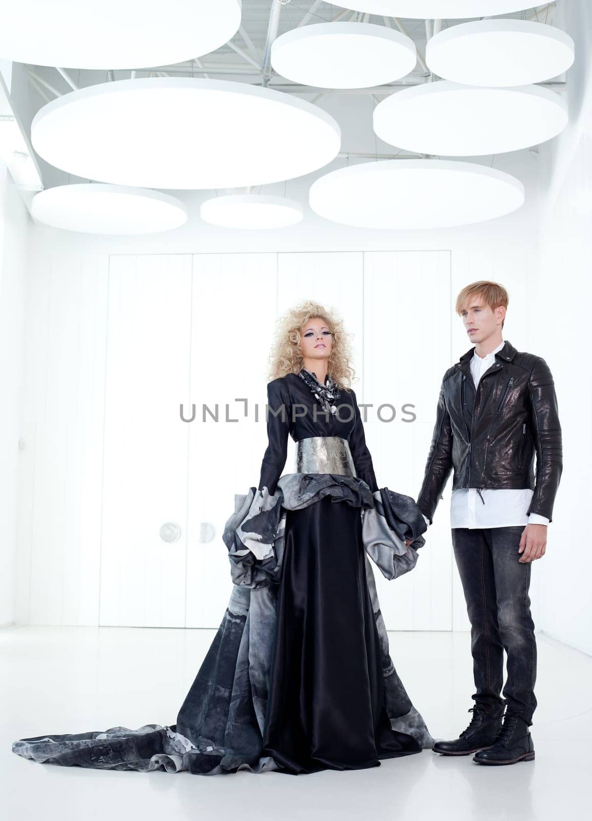Black haute couture retro futurist couple in modern white hall with vampire inspiration