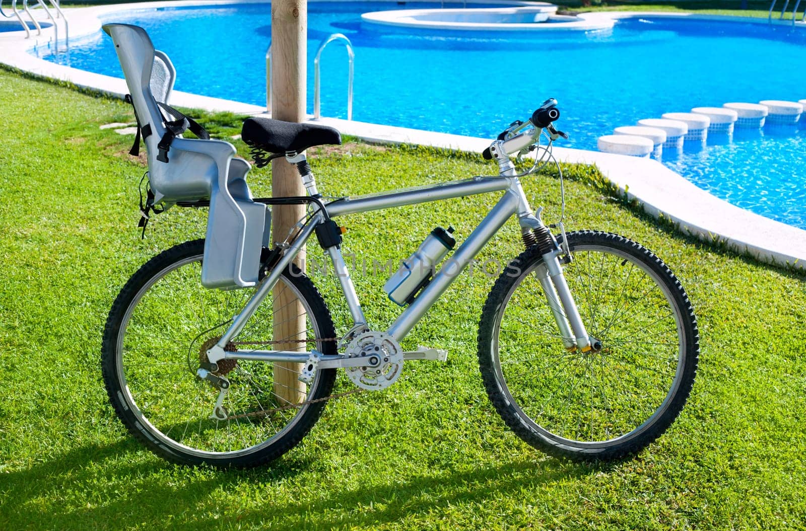bicycle with baby seat in grass pool outdoor on summer vacation
