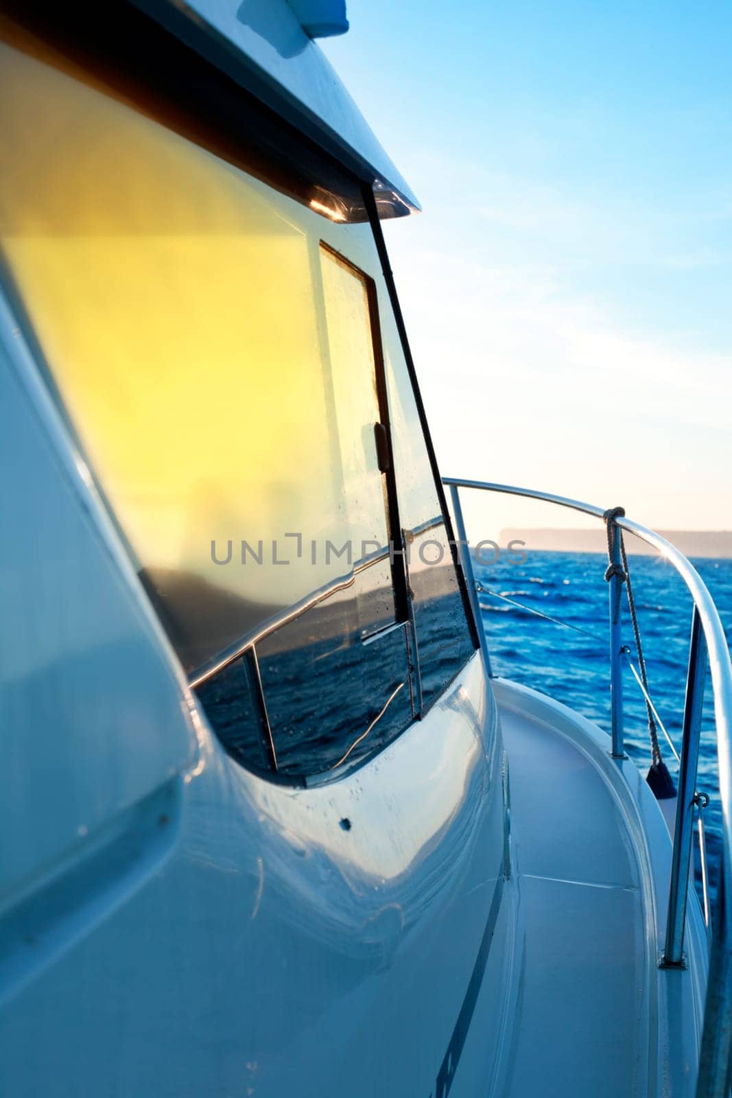 blue golden sunrise sailing on boat side with Mediterranean coastline in horizon