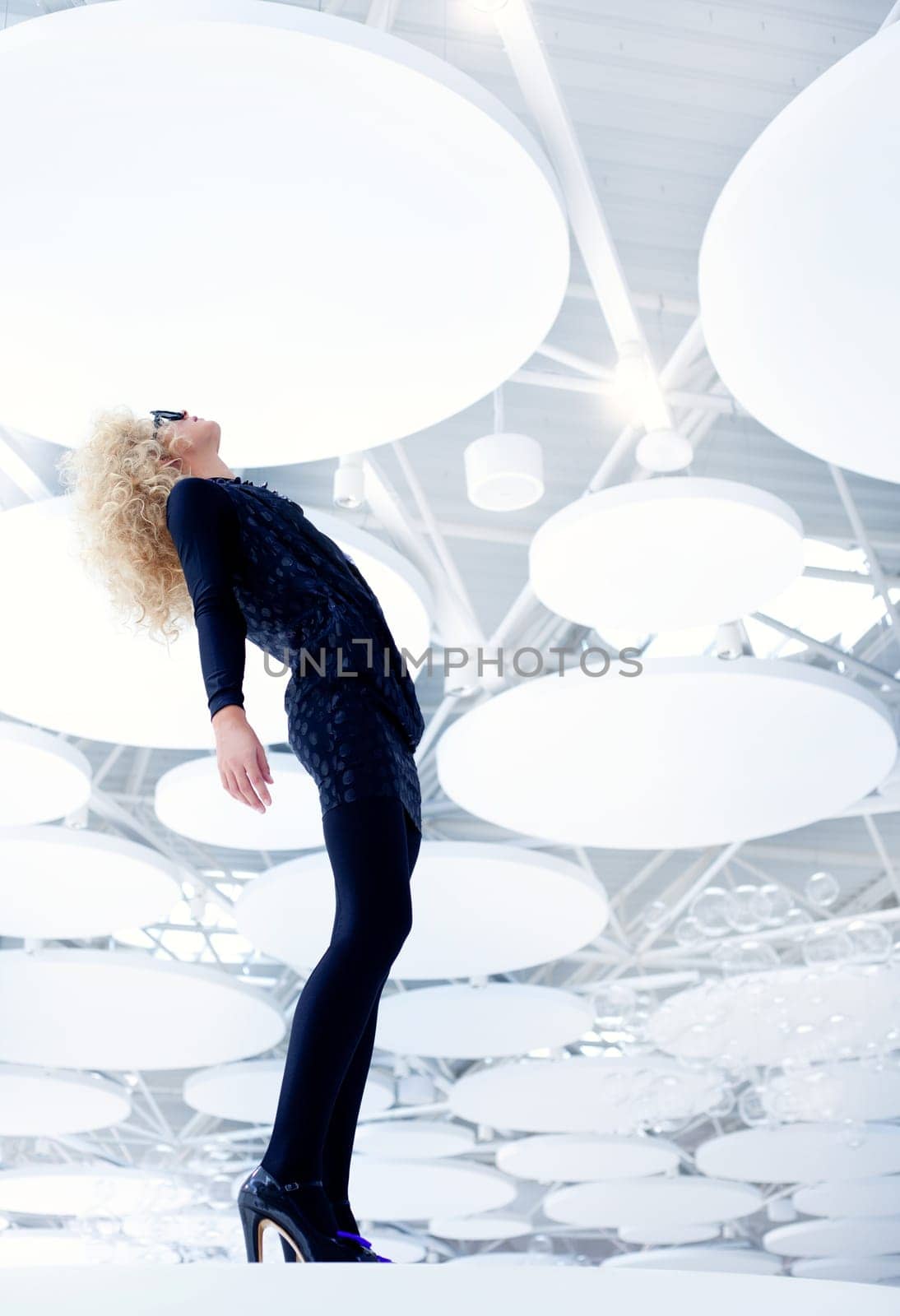 Blond futuristic vintage sexy woman in black on modern indoor full length