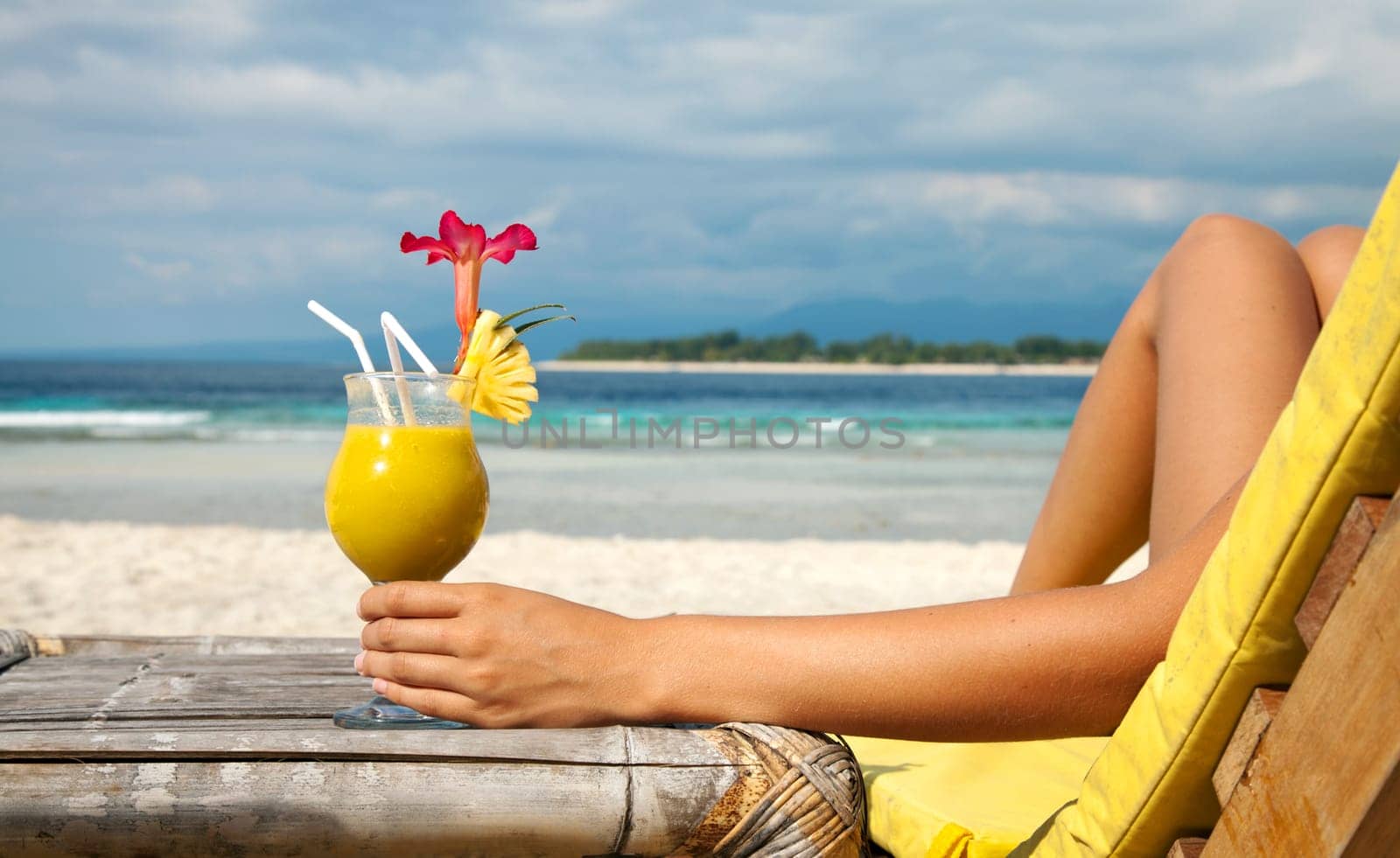 Woman holding a fruit cocktail on a tropical beach