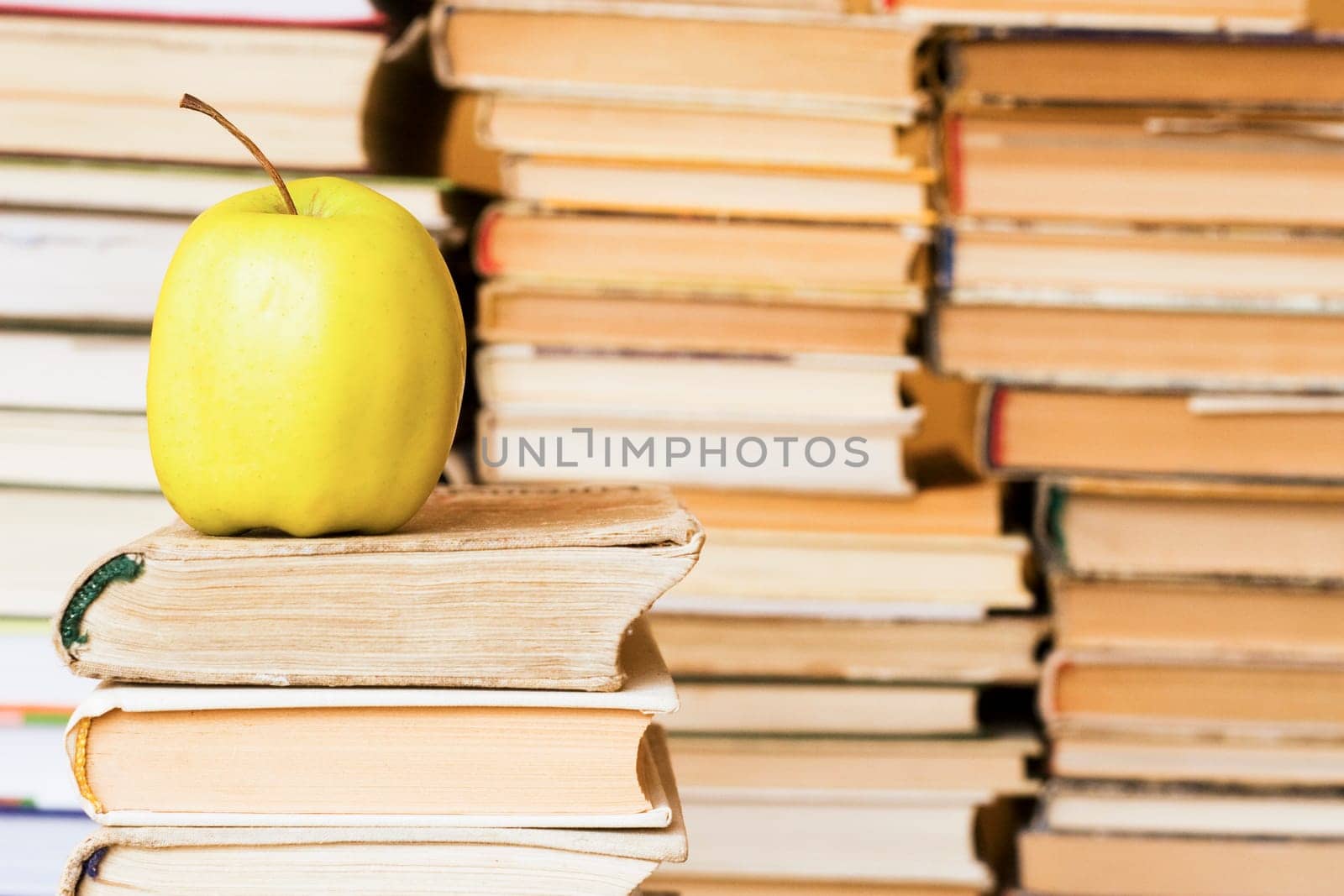 yellow apple on stack of books at library
