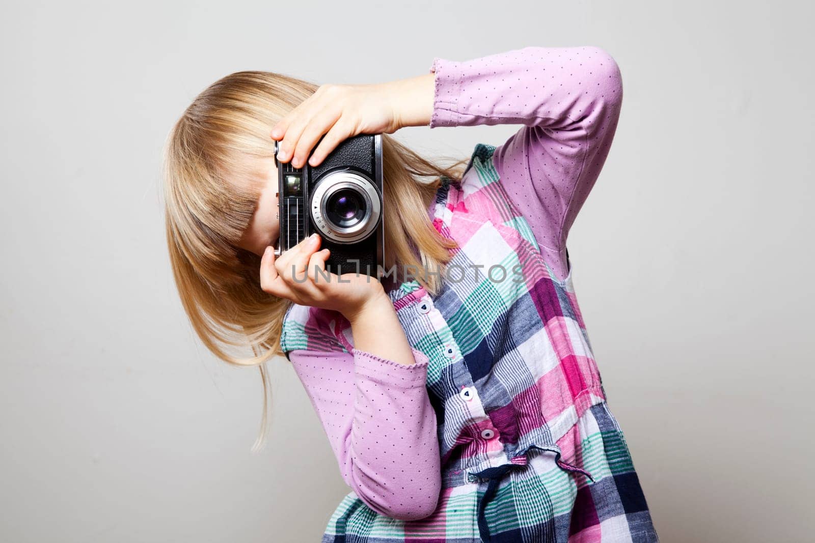 Little girl with a vintage camera. Studio shot.