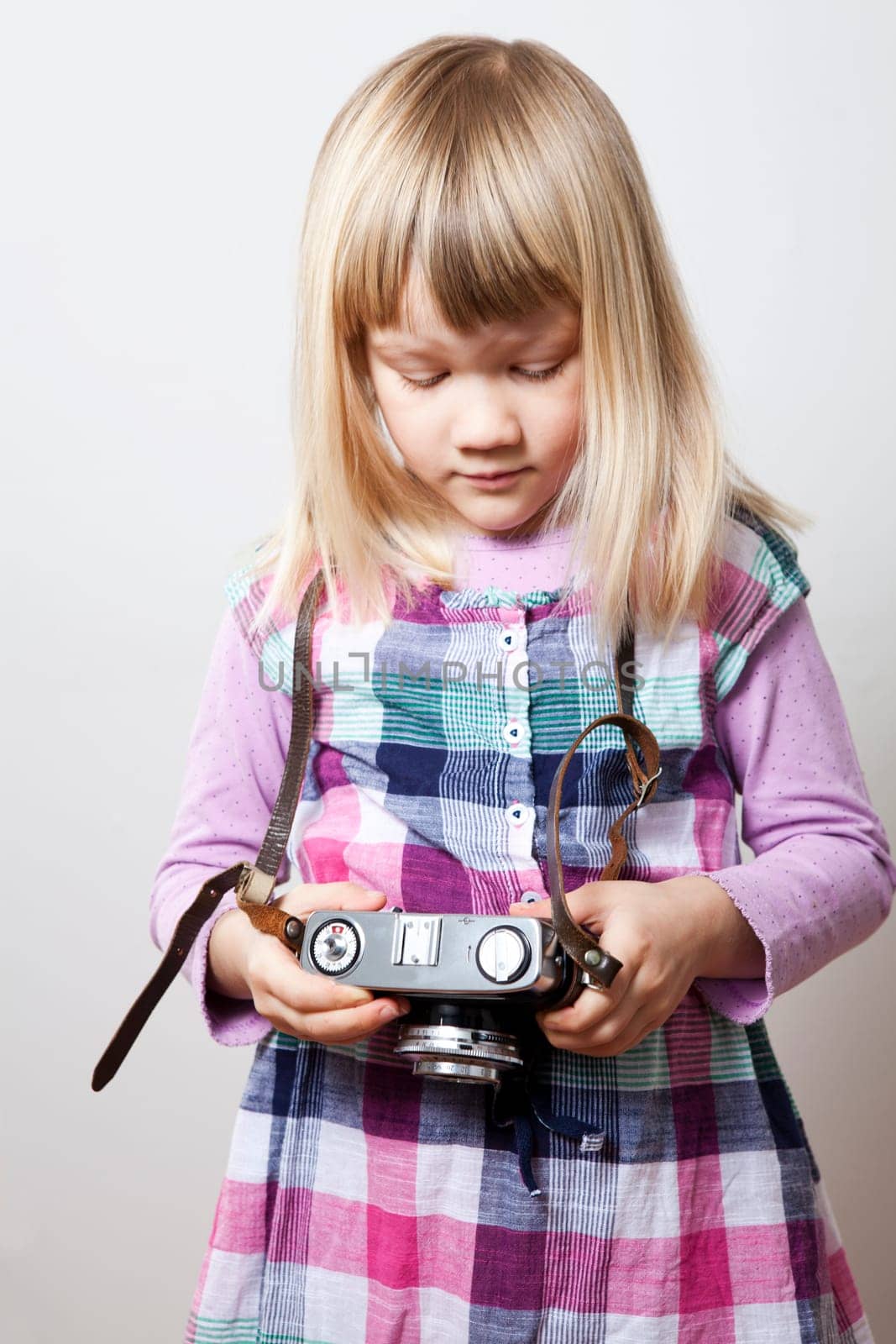 Little girl with a vintage camera. Studio shot.