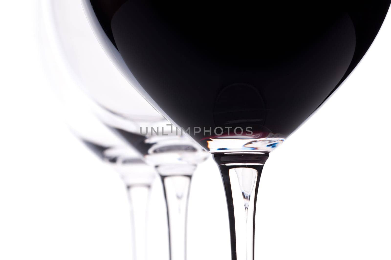 Three wine glasses backlit,one of which contains red wine from Bordeaux