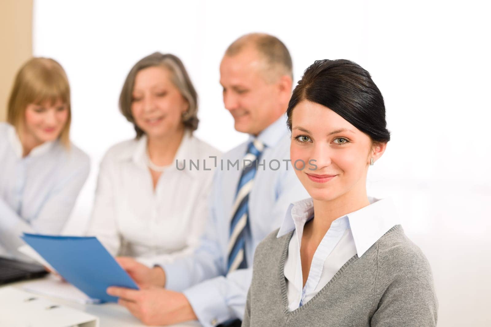 Young executive woman looking camera during meeting with team colleagues