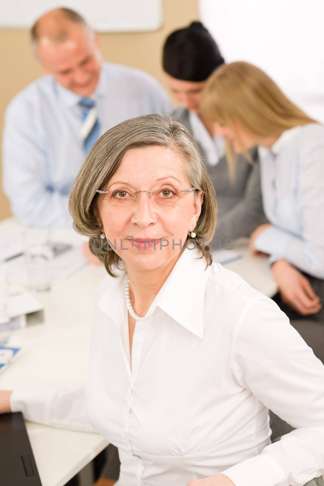 Business team meeting executive senior businesswoman with colleagues in background