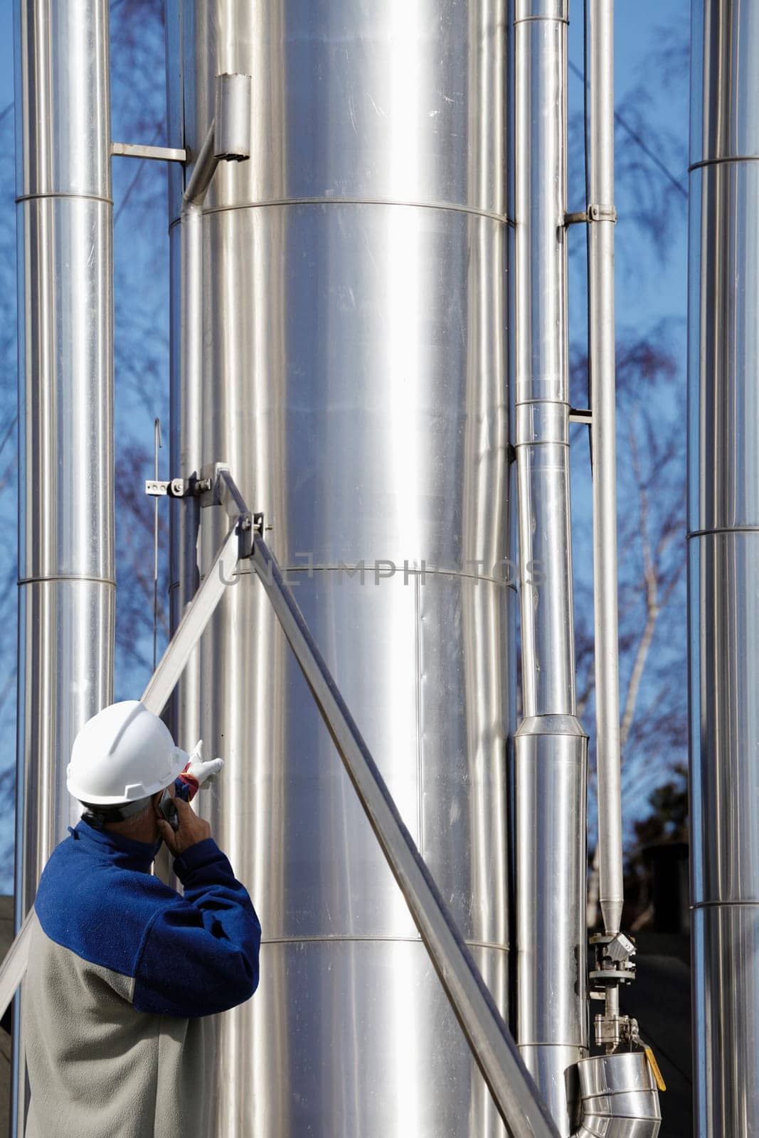 engineer, worker, pointing at large pipelines, oil, gas and fuel