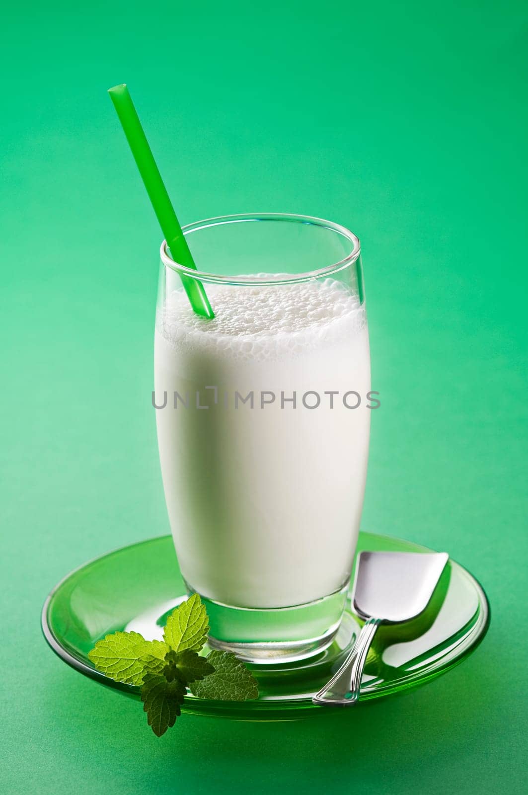 Fresh milk in tall glass on green background