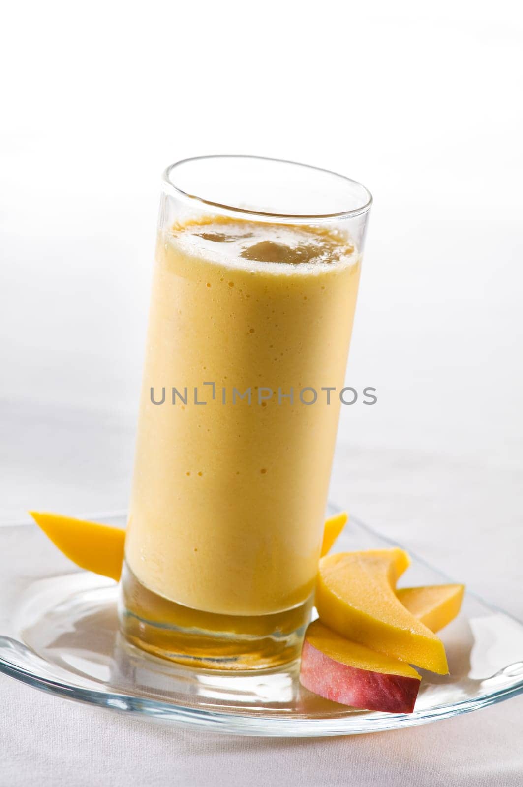 Fresh mango smoothie in tall glass close up