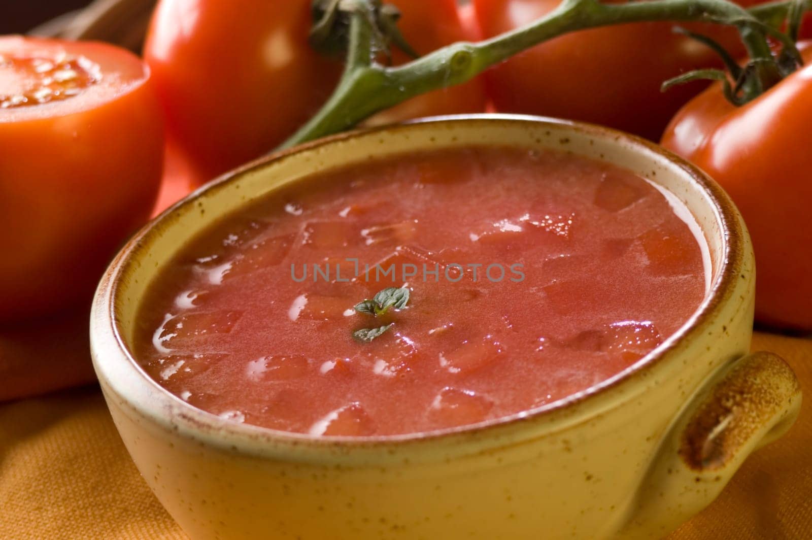 tomato soup with tomatoes in background close up