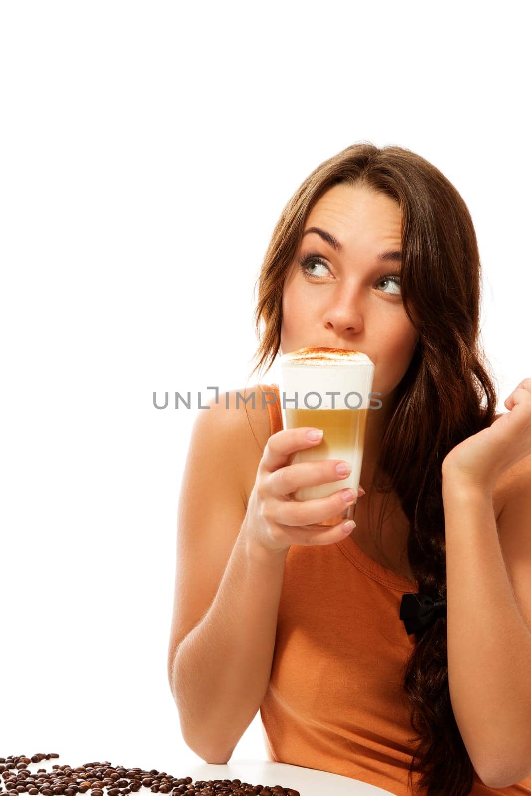 Young woman drinking latte macchiato coffee and looking up against white background