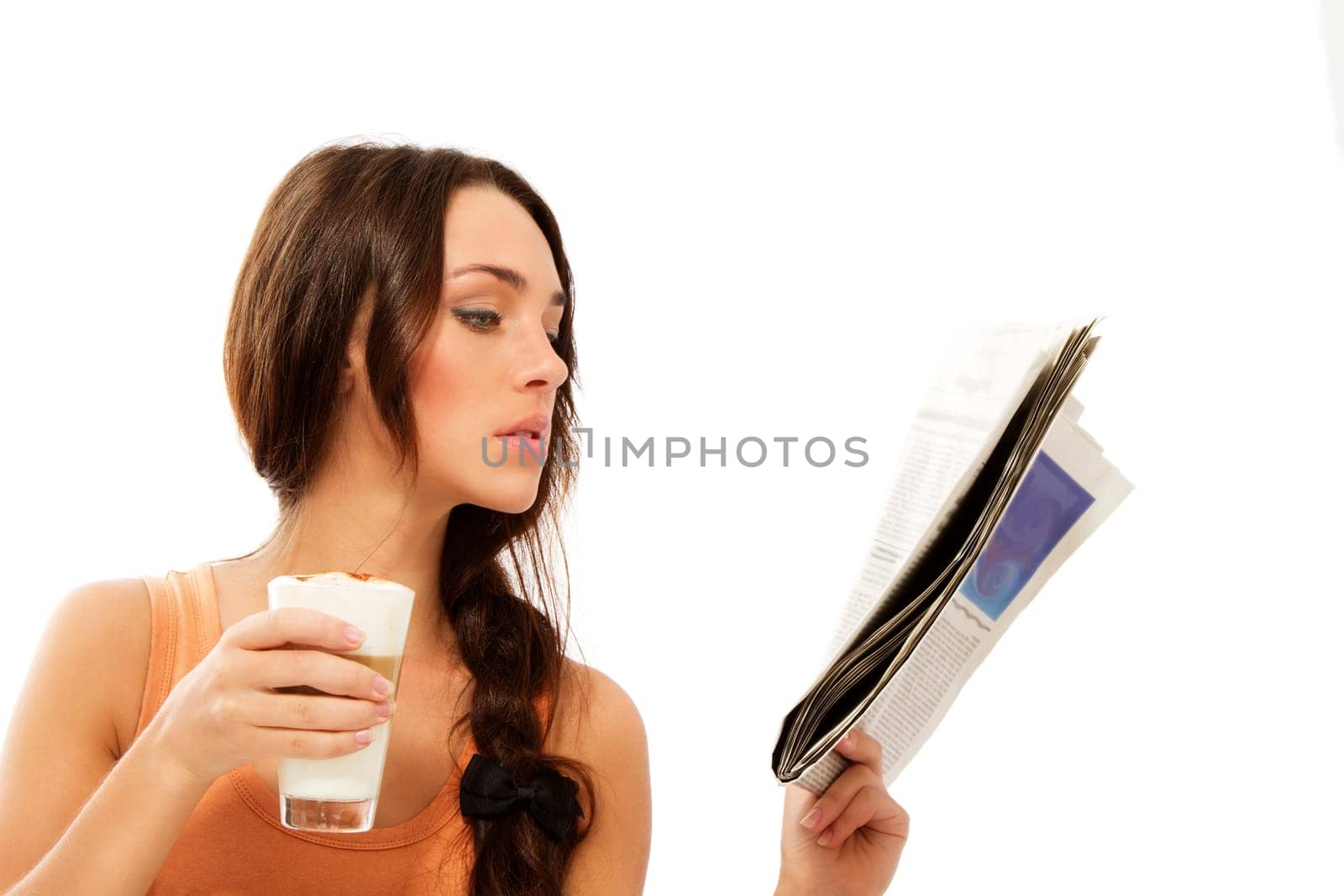 Young woman with a glass of latte macchiato coffee reading newspaper against white background