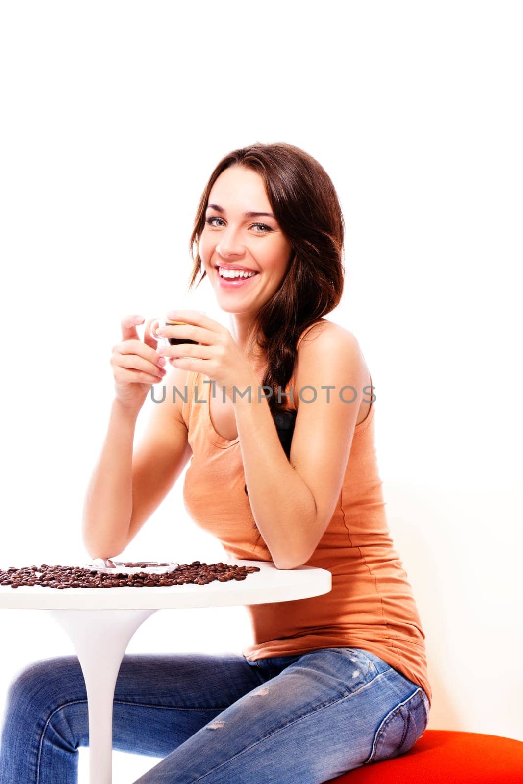 Cheerful woman sitting at a table with espresso coffee against white background