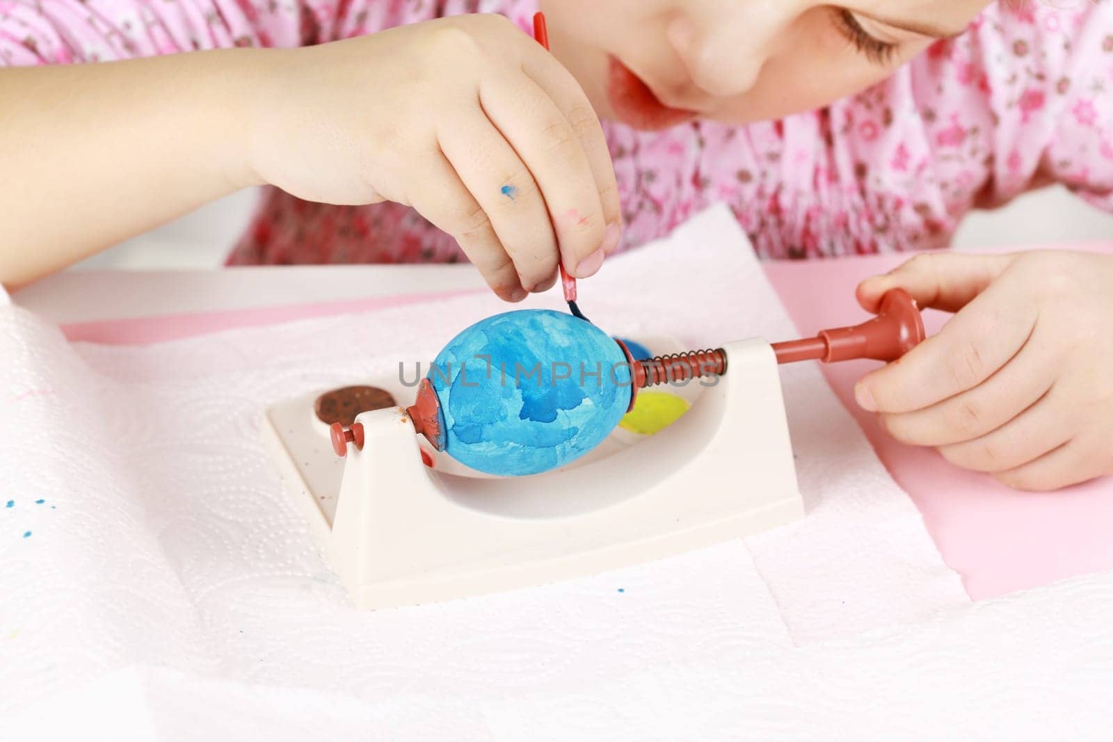 Cute little girl painting Easter eggs