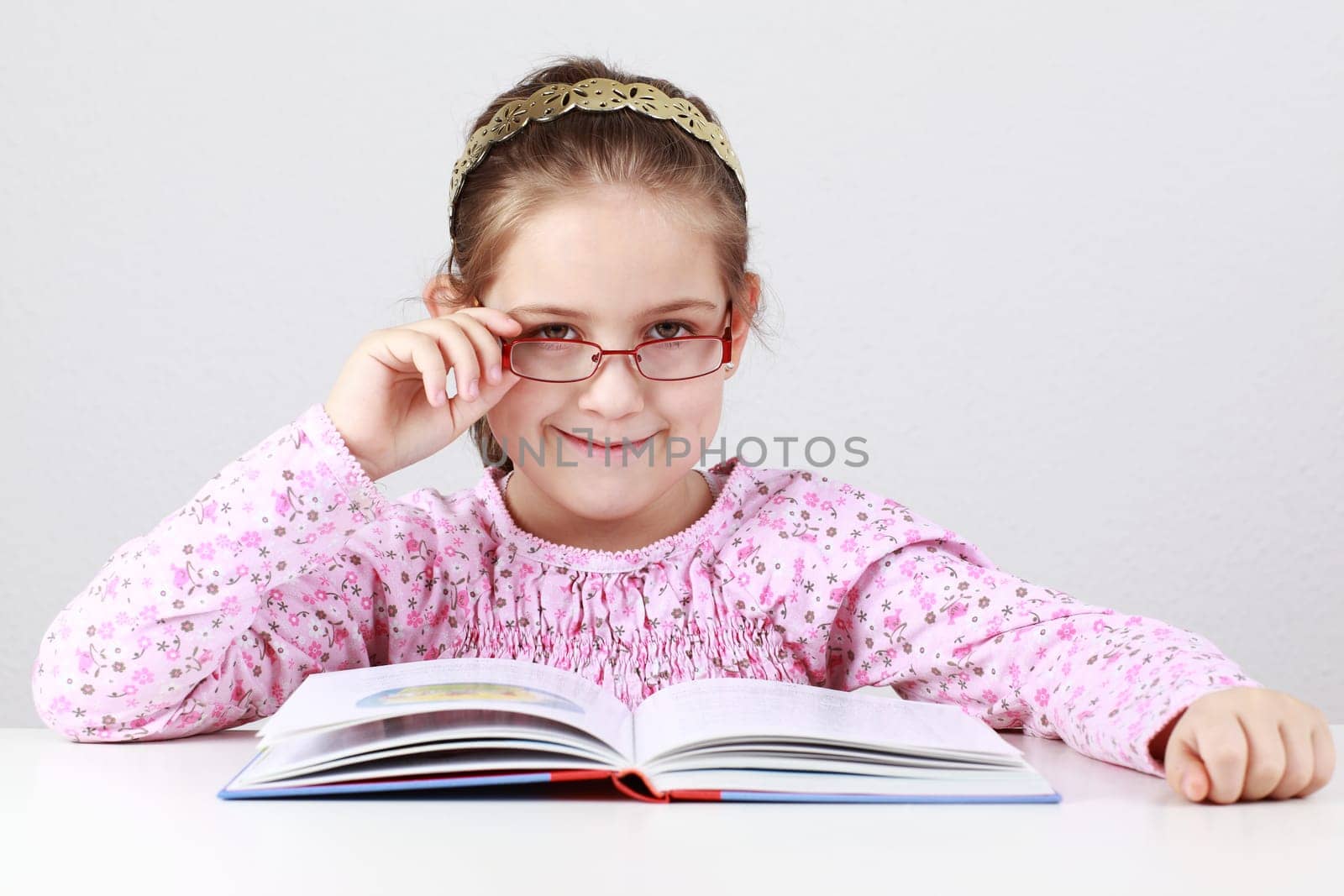 Cute schoolgirl with glasses reading book