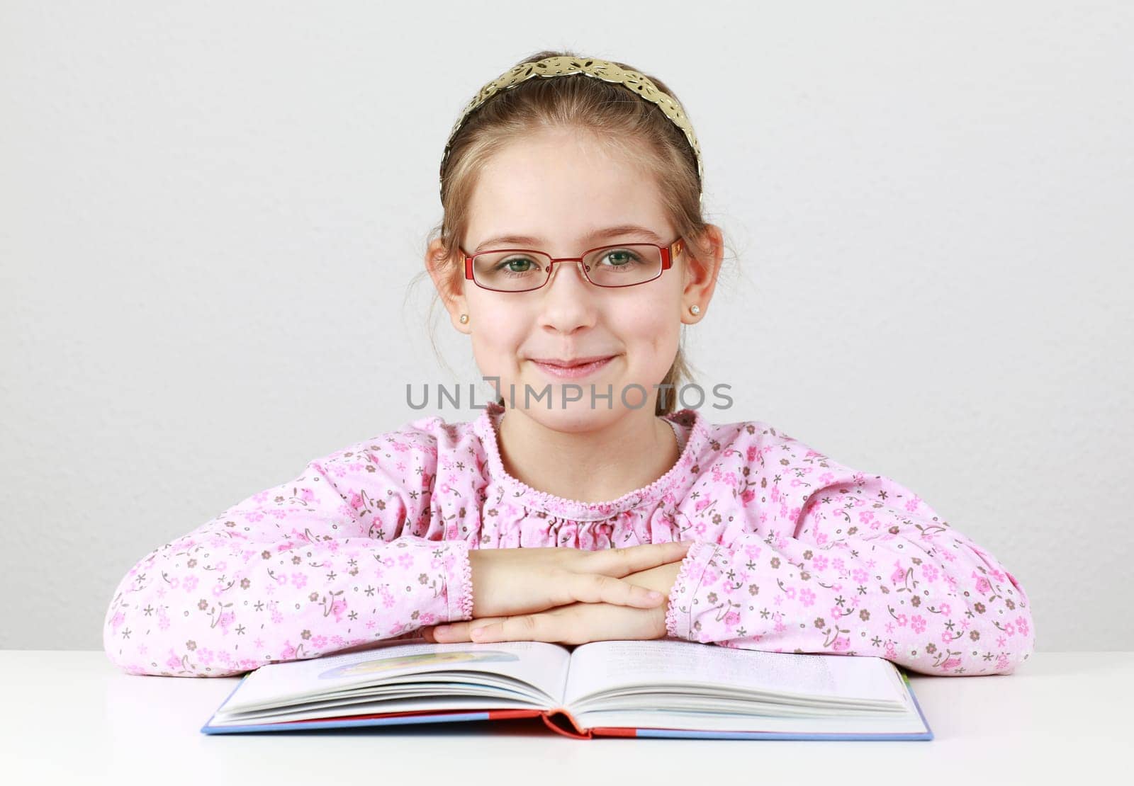 Cute schoolgirl with glasses reading book