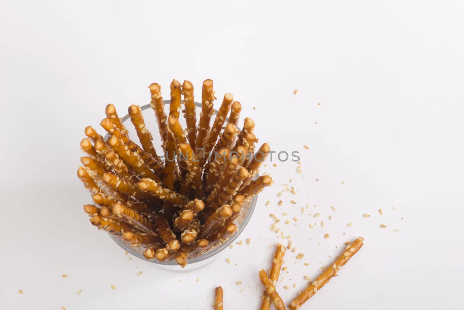 Pretzel sticks in a glass,many crumbs around the outside,photographed from above