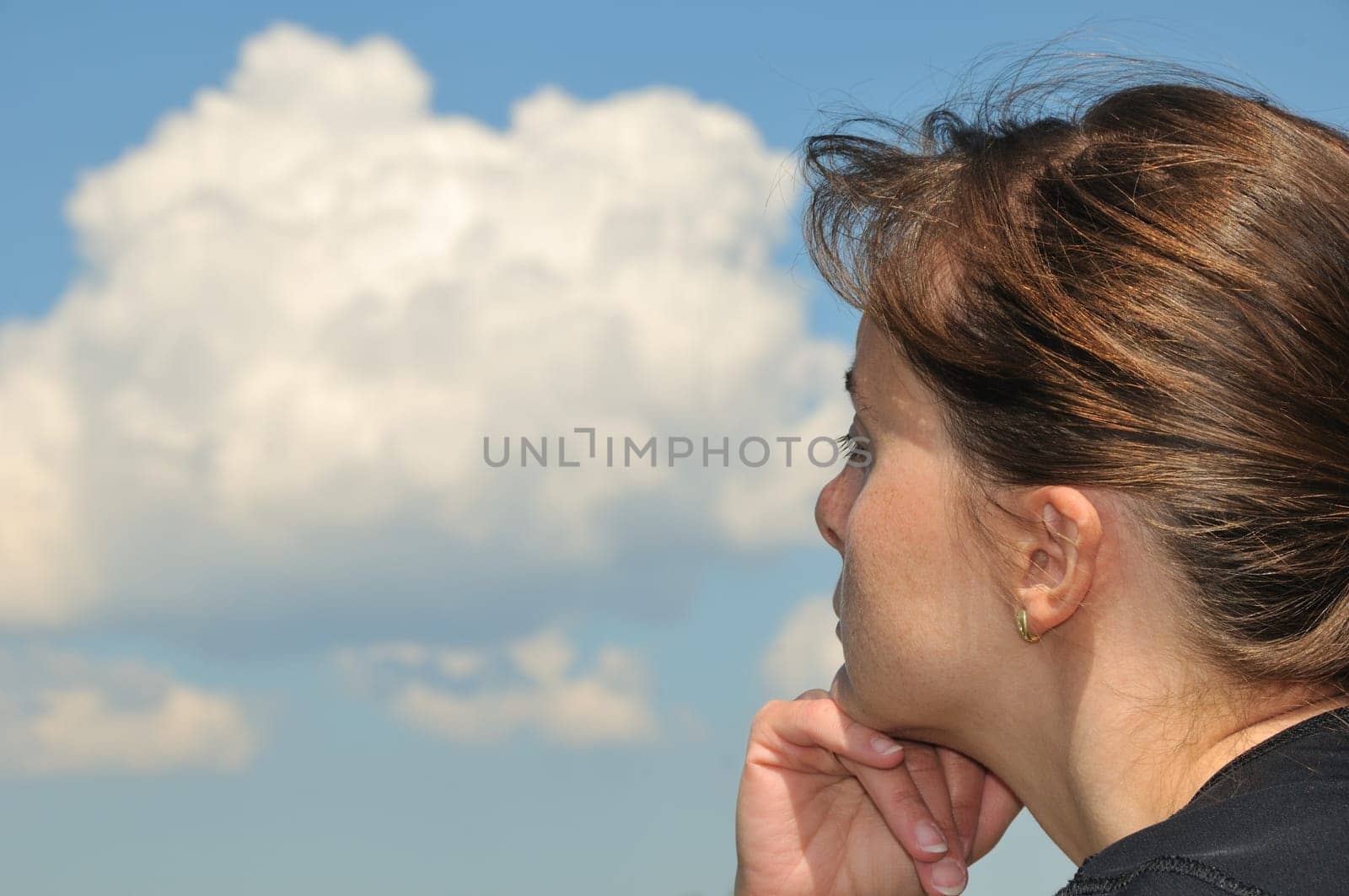 Head of Young woman dreaming in day with blue sky and white clouds in background - detail